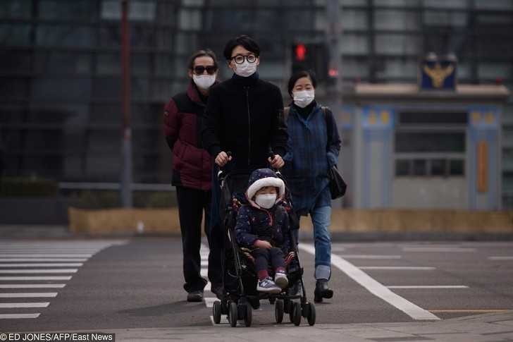 Rodzina nosząсa maski podczas szczególniе zanieczyszczonego dnia w Seulu.