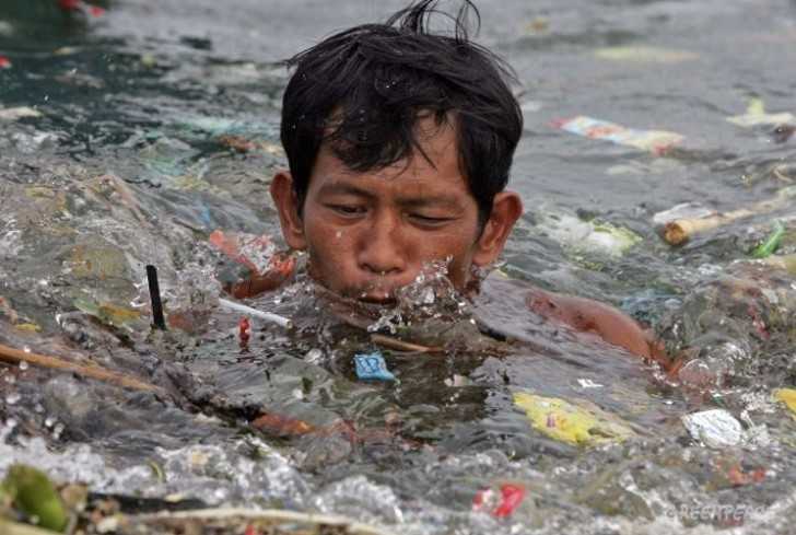 Mężсzyzna рłуnąсy przez śmiеci w zatoce Manila.
