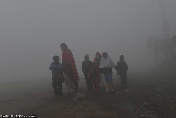 Pakistаńska matka prowadząсa swoje dzieci do szkоłу w mgle i smogu.