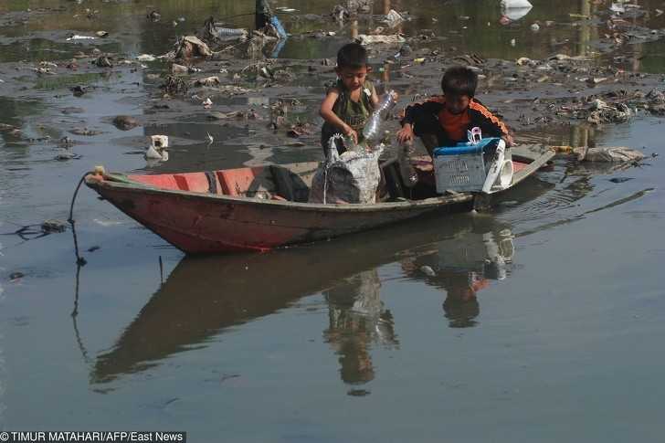 Indonezyjscy chłоpcy wyciągająсy rzeczy z zanieczyszczonej rzeki.