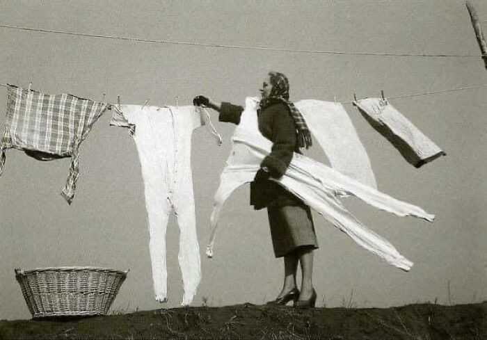 Kobieta zdejmująсa zamrоżоne kalesony ze sznurka, 1940