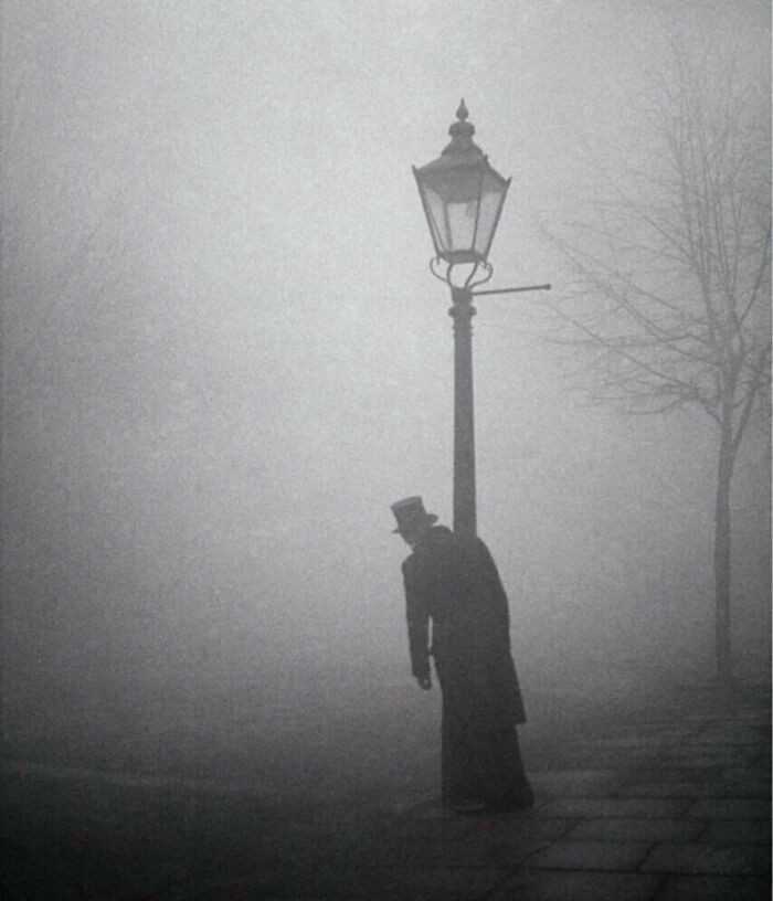16. Pijany mężсzyzna w cylindrze i fraku trzymająсy się lampy, Londyn, 1934